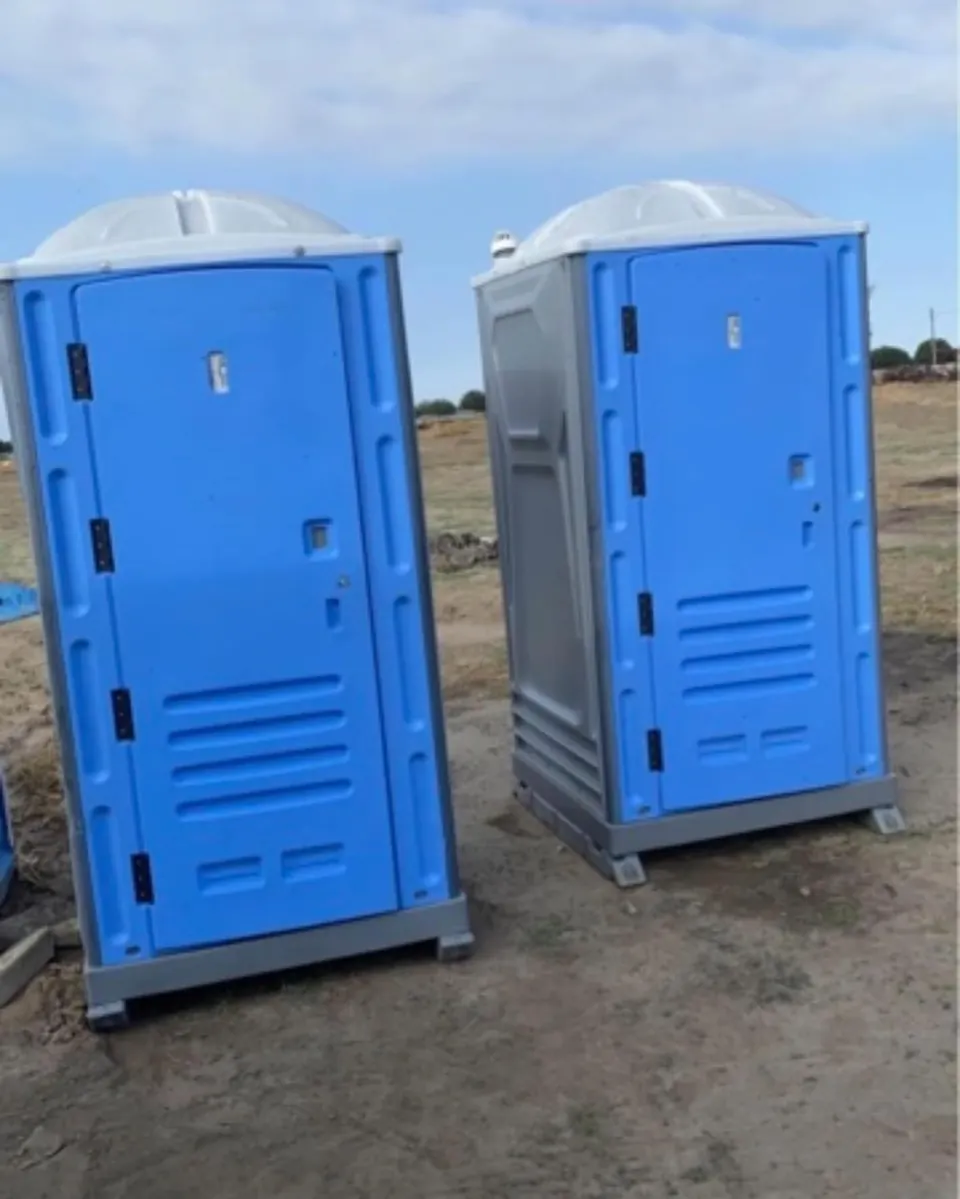 Two blue portable toilets on a work site